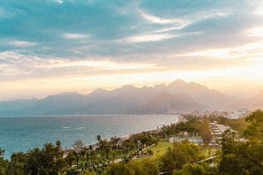 Stunning aerial view of Antalya's coastline with mountains and sea at sunset.