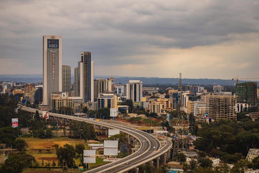 Aerial view of Nairobi's modern skyline and expressway under cloudy skies.
